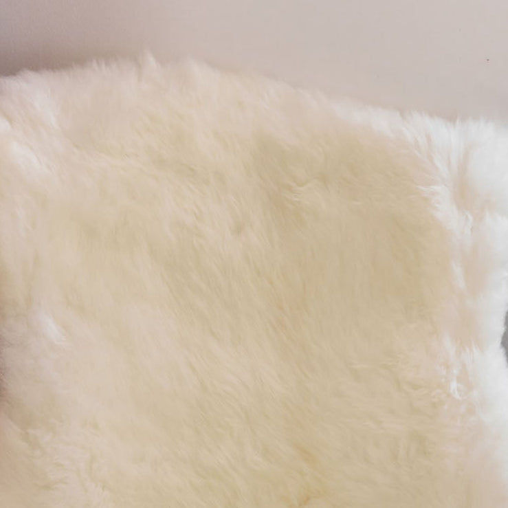 A white sheepskin rug or hide draped over a dark wooden chair in a home interior setting.