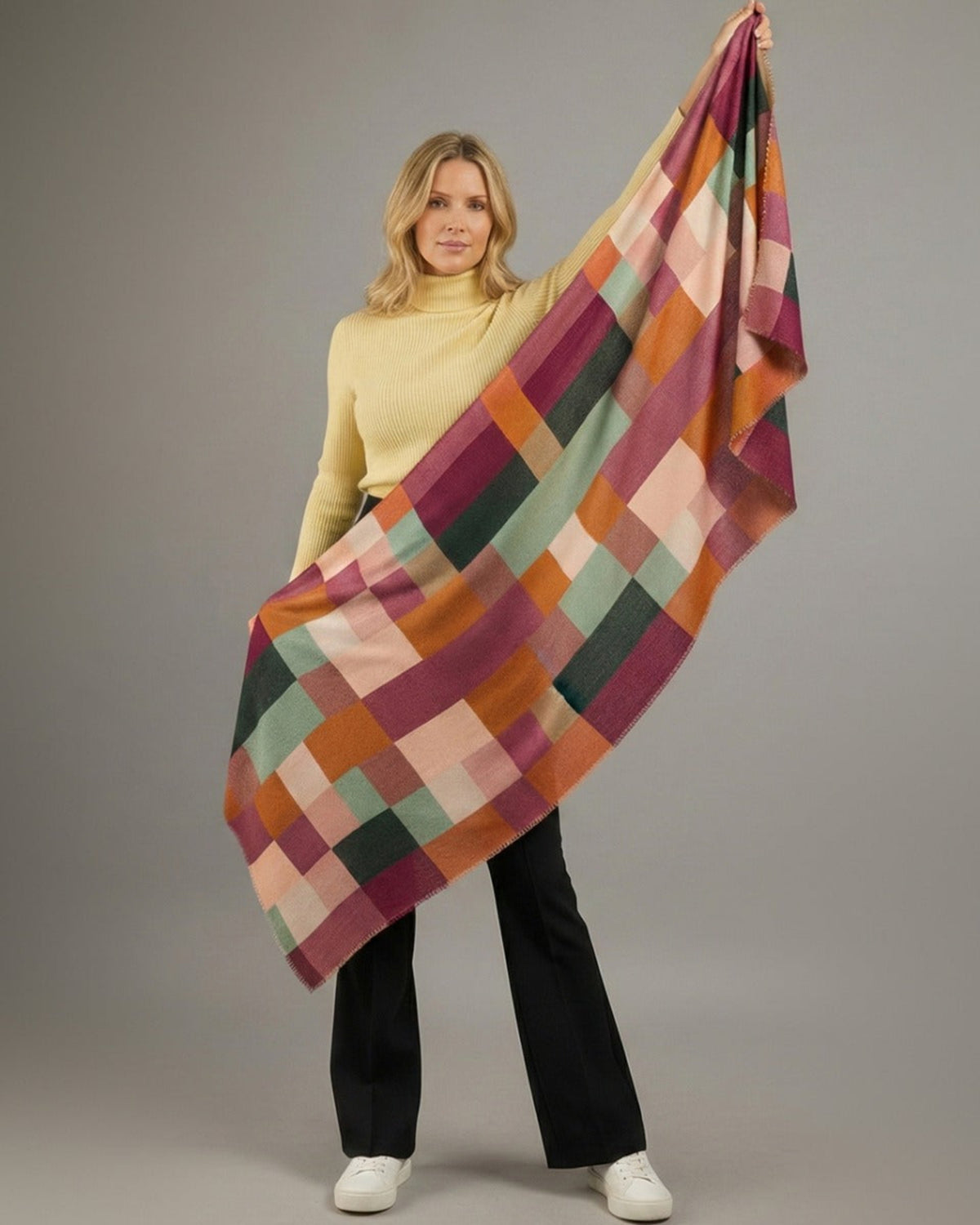 Woman holding a colorful checkered scarf against a gray background
