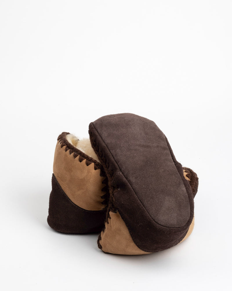 Pair of brown and beige sheepskin slippers on a white background