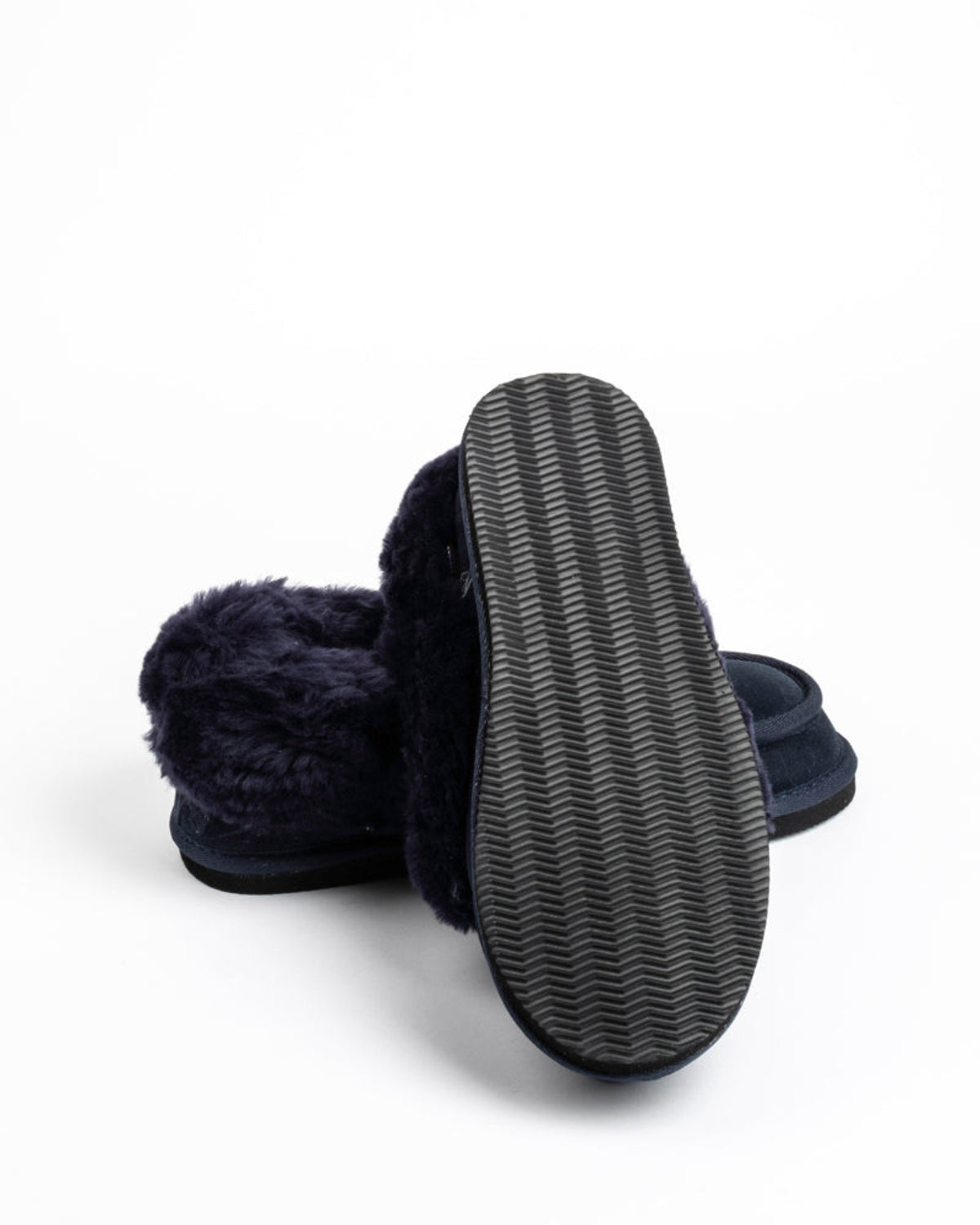 Dark blue sheepskin slipper with textured sole on a white background