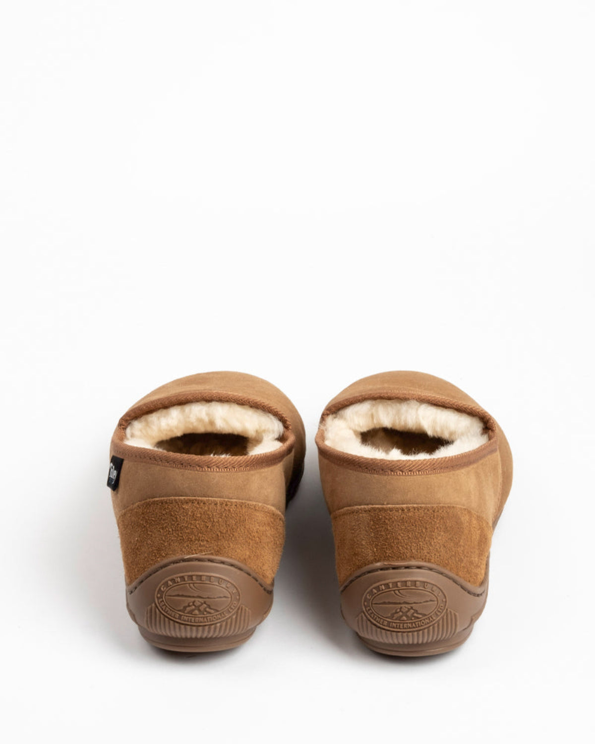 Pair of brown sheepskin slippers with fur lining on a white background
