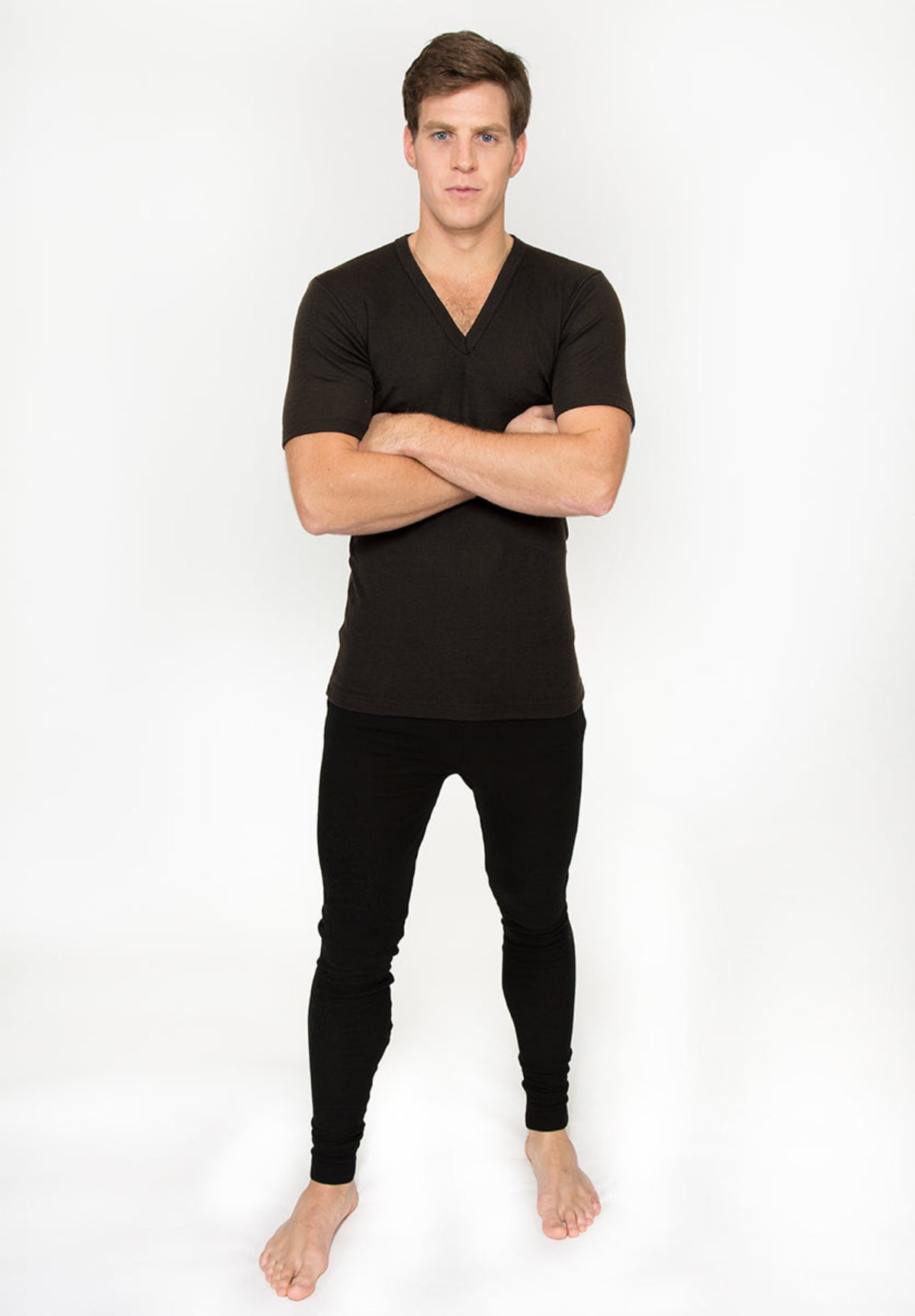 Man wearing a merino black V-neck shirt and black pants on a white background